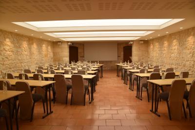 Un groupe de personnes joue au ballon sur une pelouse devant un grand bâtiment ancien sous un ciel dégagé.