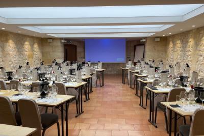 Un groupe de personnes joue au ballon sur une pelouse devant un grand bâtiment ancien sous un ciel dégagé.