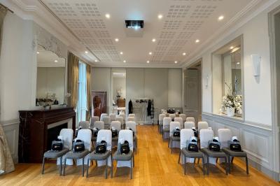 Un groupe de personnes joue au ballon sur une pelouse devant un grand bâtiment ancien sous un ciel dégagé.