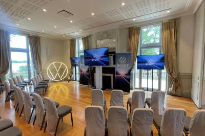 Un groupe de personnes joue au ballon sur une pelouse devant un grand bâtiment ancien sous un ciel dégagé.