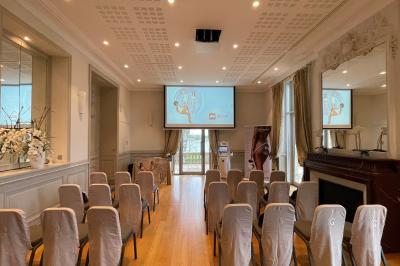 Un groupe de personnes joue au ballon sur une pelouse devant un grand bâtiment ancien sous un ciel dégagé.