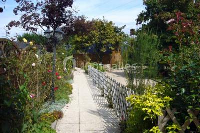Un jardin avec pelouse, arbres variés et un lampadaire, éclairé par une lumière douce du matin.