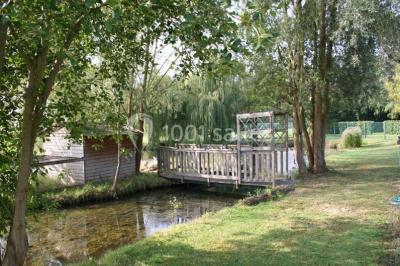 Un jardin avec pelouse, arbres variés et un lampadaire, éclairé par une lumière douce du matin.