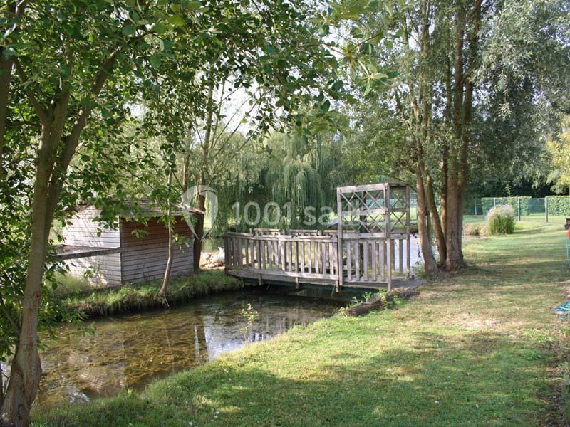 Petit pont en bois traversant un ruisseau entouré d'arbres et de verdure dans un cadre paisible.