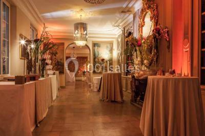 Vue d'une pièce lumineuse avec sol en carreaux anciens, mobilier classique et une chambre attenante avec lit à baldaquin.