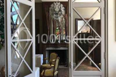 Vue d'une pièce lumineuse avec sol en carreaux anciens, mobilier classique et une chambre attenante avec lit à baldaquin.