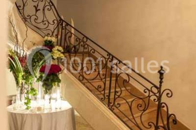 Vue d'une pièce lumineuse avec sol en carreaux anciens, mobilier classique et une chambre attenante avec lit à baldaquin.