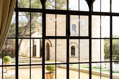 Vue d'une pièce lumineuse avec sol en carreaux anciens, mobilier classique et une chambre attenante avec lit à baldaquin.