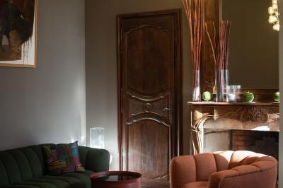 Vue d'une pièce lumineuse avec sol en carreaux anciens, mobilier classique et une chambre attenante avec lit à baldaquin.