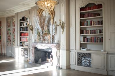Vue d'une pièce lumineuse avec sol en carreaux anciens, mobilier classique et une chambre attenante avec lit à baldaquin.