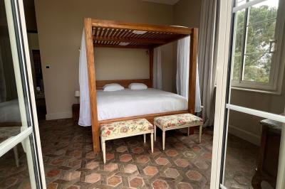 Vue d'une pièce lumineuse avec sol en carreaux anciens, mobilier classique et une chambre attenante avec lit à baldaquin.