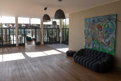 Tour en pierre entourée de végétation, avec bassin d'eau, chaises et tables en métal sur une terrasse ensoleillée.
