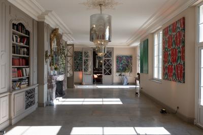 Tour en pierre entourée de végétation, avec bassin d'eau, chaises et tables en métal sur une terrasse ensoleillée.