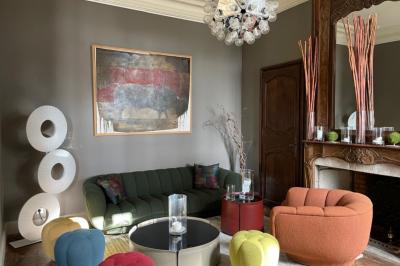 Tour en pierre entourée de végétation, avec bassin d'eau, chaises et tables en métal sur une terrasse ensoleillée.