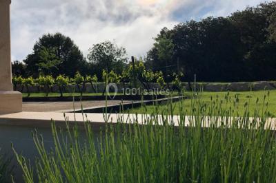 Miniature Location salle Rognes (Bouches-du-Rhône) - Domaine Naïs #6 Terrasse en pierre avec des tonneaux en bois, vue sur un paysage verdoyant et une clôture en fer forgé.