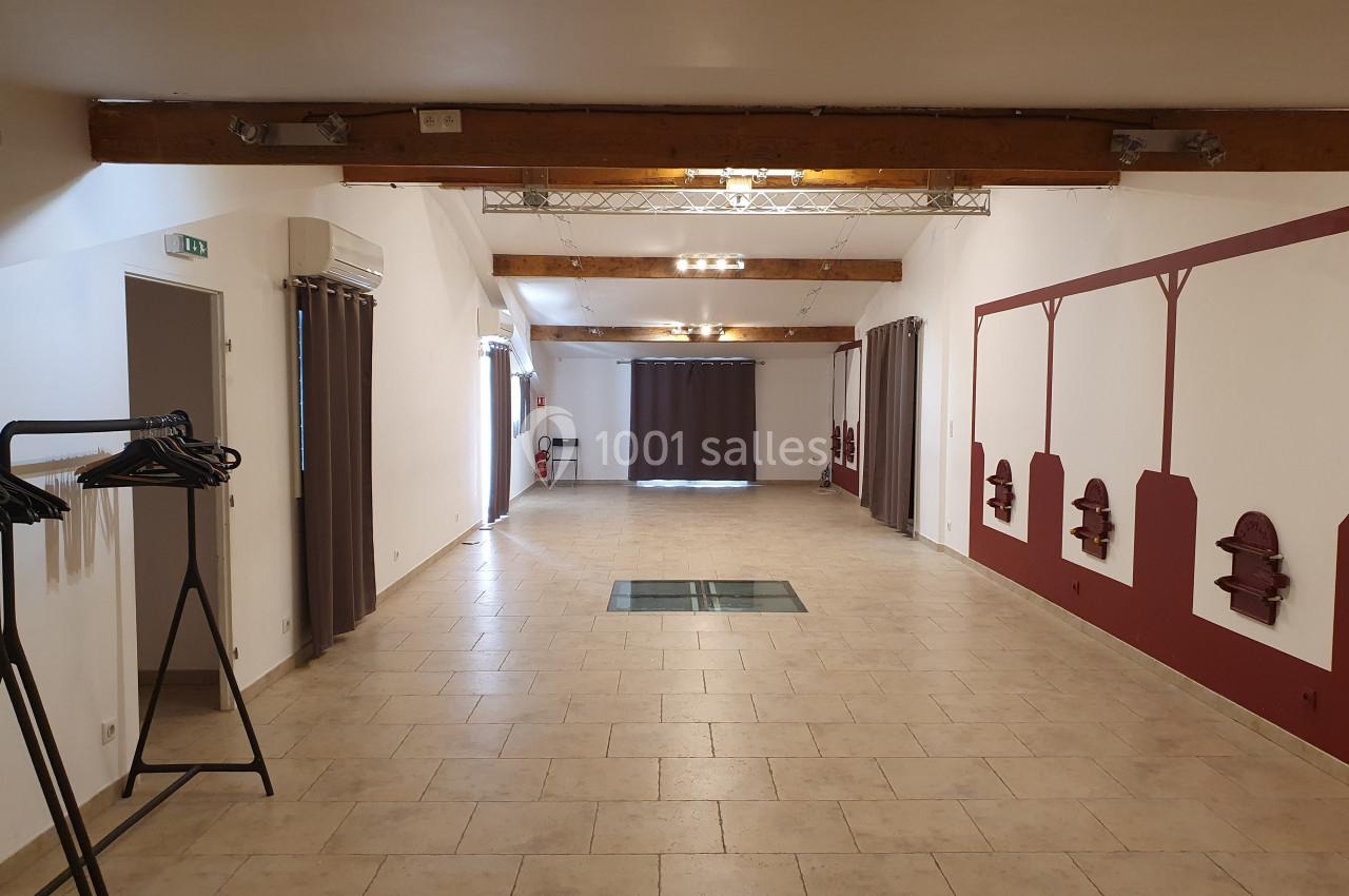 Location salle Rognes (Bouches-du-Rhône) - Domaine Naïs #23 Salle vide avec carrelage beige, poutres apparentes, murs blancs et rouges, et portants à vêtements sur la gauche.