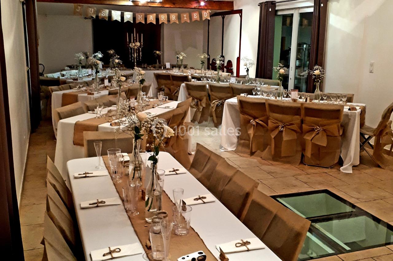 Location salle Rognes (Bouches-du-Rhône) - Domaine Naïs #20 Salle décorée pour un événement, avec tables alignées, nappes blanches, chemins de table en jute et chaises ornées de nœuds.