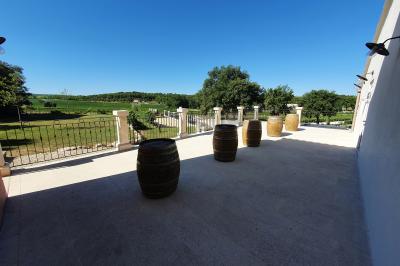 Miniature Location salle Rognes (Bouches-du-Rhône) - Domaine Naïs #24 Terrasse en pierre avec des tonneaux en bois, vue sur un paysage verdoyant et une clôture en fer forgé.