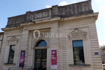 Salle d'exposition avec des œuvres accrochées aux murs, tables hautes et projection lumineuse ’Réseau AMA’.