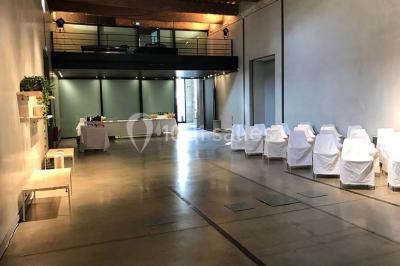 Salle d'exposition avec des œuvres accrochées aux murs, tables hautes et projection lumineuse ’Réseau AMA’.