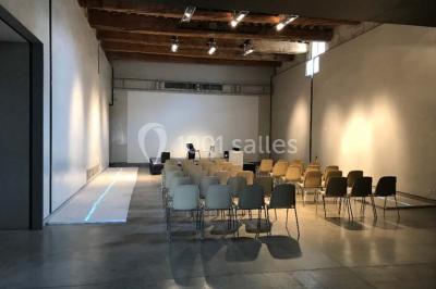 Salle d'exposition avec des œuvres accrochées aux murs, tables hautes et projection lumineuse ’Réseau AMA’.