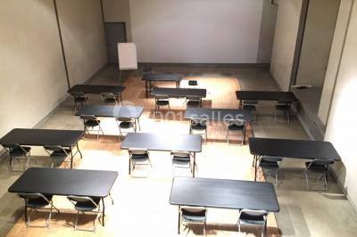 Salle d'exposition avec des œuvres accrochées aux murs, tables hautes et projection lumineuse ’Réseau AMA’.