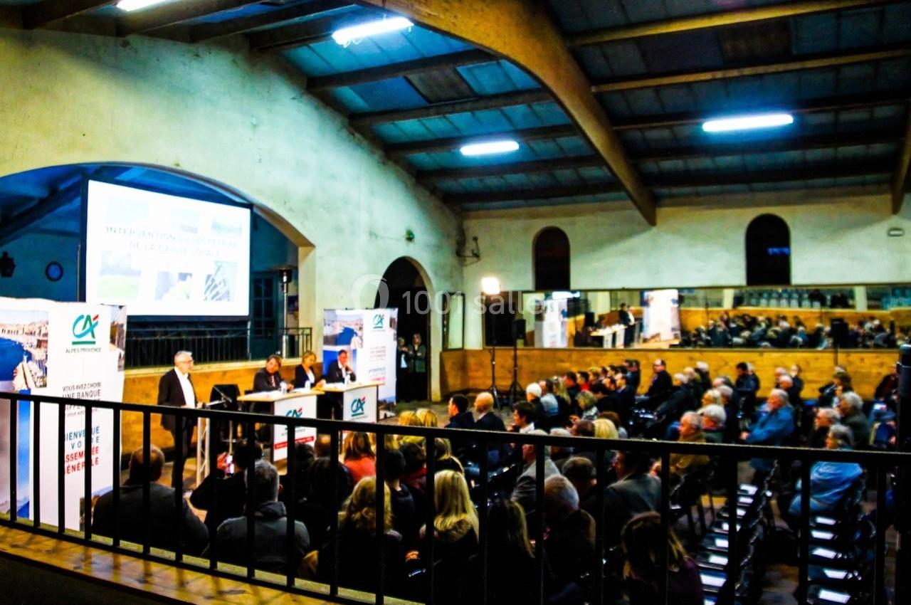Salle de conférence avec un public assis, des intervenants sur scène et une projection sur écran.