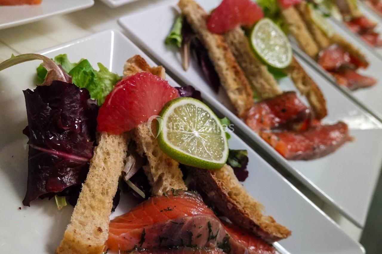Assiettes de saumon mariné avec tranches de pain, salade verte, quartiers de pamplemousse et rondelles de citron vert.