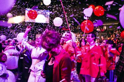 Assortiment de fromages et saumon fumé sur une table avec une bouteille de vin rouge, verres et cheminée en arrière-plan.