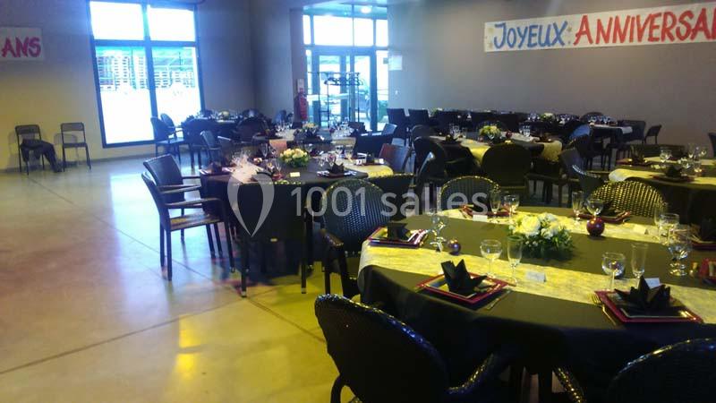 Salle décorée pour un anniversaire avec tables dressées, nappes colorées, serviettes pliées et compositions florales.