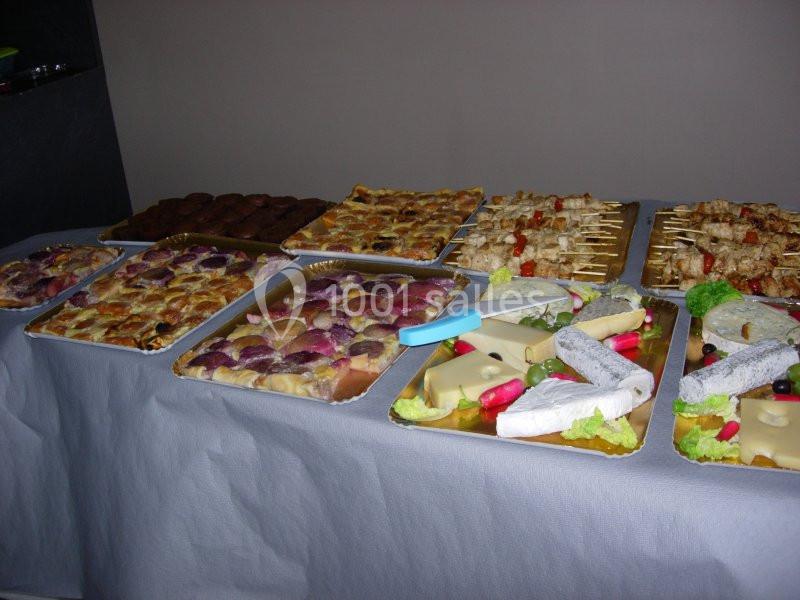 Buffet avec divers plats, incluant quiches, brochettes, fromages et charcuteries, présentés sur une table recouverte d'une…