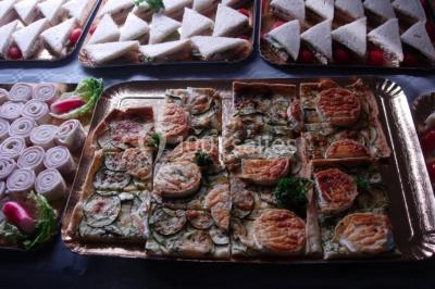 Table ronde dressée avec des verres, couverts et serviettes vertes, entourée de chaises, avec un buffet en arrière-plan.