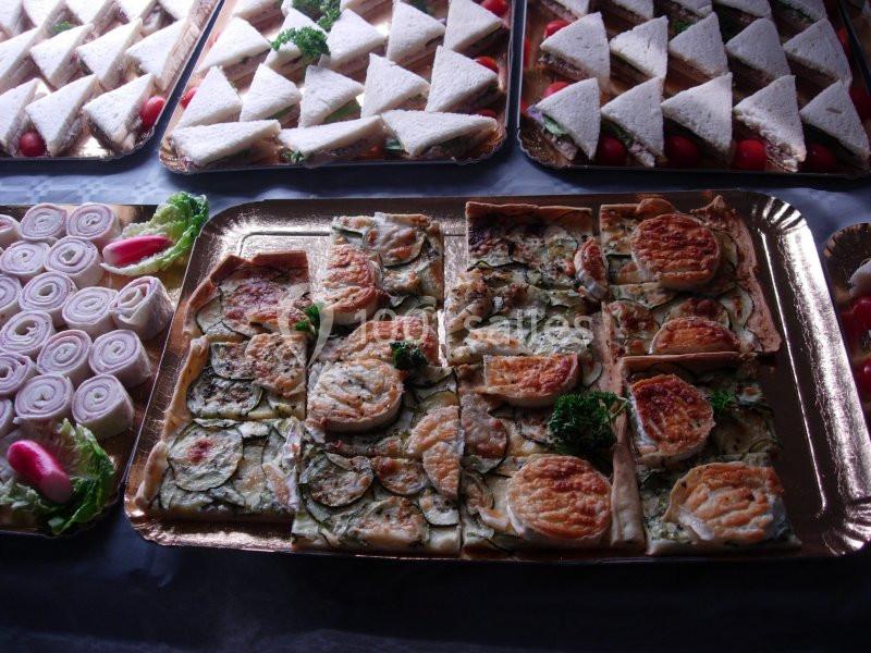 Plateaux de tartes salées aux légumes et de sandwichs triangulaires garnis, présentés pour un buffet.