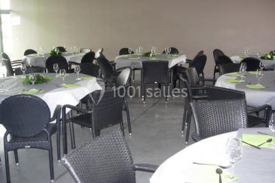 Table ronde dressée avec des verres, couverts et serviettes vertes, entourée de chaises, avec un buffet en arrière-plan.