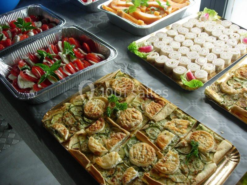 Plateaux de salades, roulés apéritifs et tartes salées disposés sur une table.
