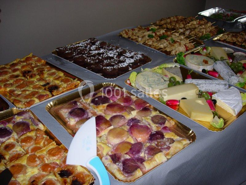Plateau de desserts variés, fromages et brochettes disposés sur une table recouverte d'une nappe grise.