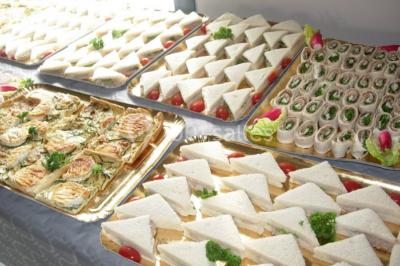 Salle avec des tables rondes dressées, nappes blanches, serviettes vertes, verres et décorations florales.