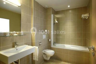 Croupier debout derrière une table de blackjack dans un casino, avec jetons et cartes visibles.