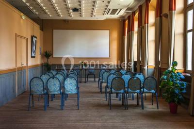 Croupier debout derrière une table de blackjack dans un casino, avec jetons et cartes visibles.