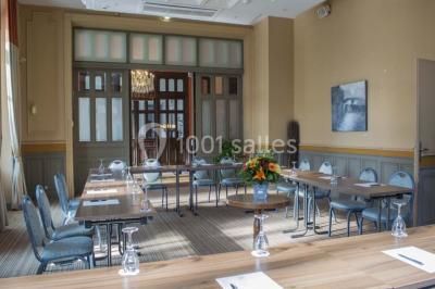 Croupier debout derrière une table de blackjack dans un casino, avec jetons et cartes visibles.