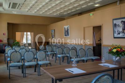 Croupier debout derrière une table de blackjack dans un casino, avec jetons et cartes visibles.