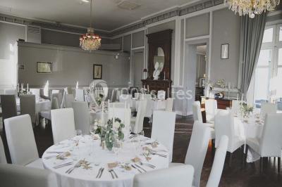 Croupier debout derrière une table de blackjack dans un casino, avec jetons et cartes visibles.