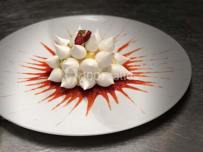 Location salle Divonne-les-Bains (Ain) - Domaine de Divonne #19 Dessert composé de meringues disposées en dôme sur un coulis rouge, décoré d'une framboise et de feuille d'or.