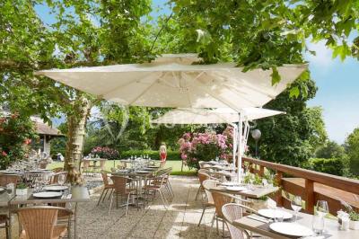 Miniature Location salle Divonne-les-Bains (Ain) - Domaine de Divonne #9 Salle de restaurant élégante avec tables dressées, chaises en bois sculpté et décor floral sur les murs et le sol.