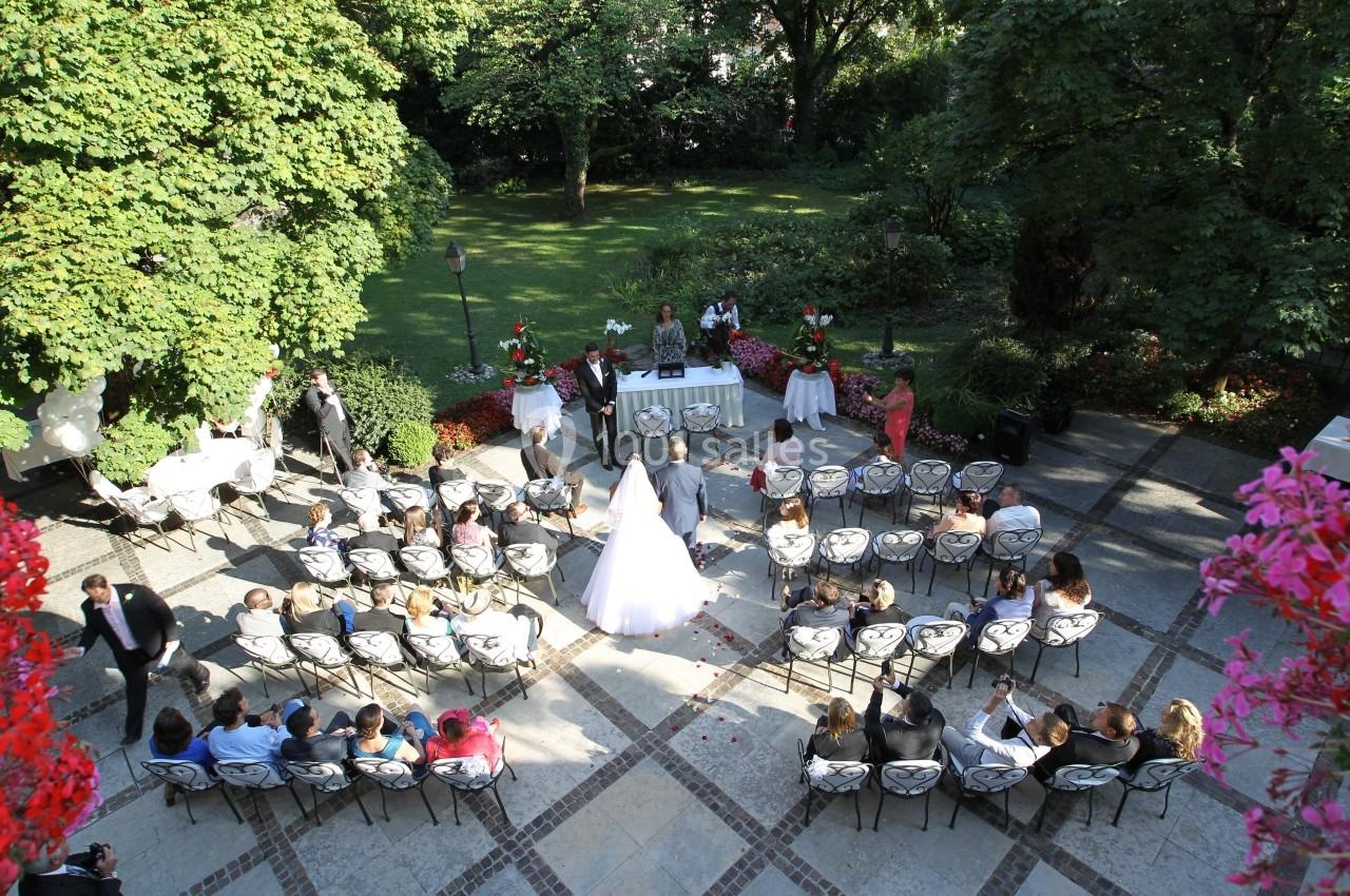 Location salle Divonne-les-Bains (Ain) - Domaine de Divonne #2 Cérémonie de mariage en plein air avec des invités assis, vue depuis le dessus, entourée de verdure et de fleurs.