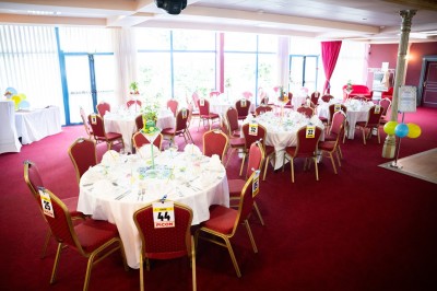 Salle de réception avec scène, piste de danse en bois, moquette rouge et plafond décoré d'une fresque.