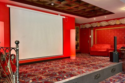 Salle de réception avec scène, piste de danse en bois, moquette rouge et plafond décoré d'une fresque.