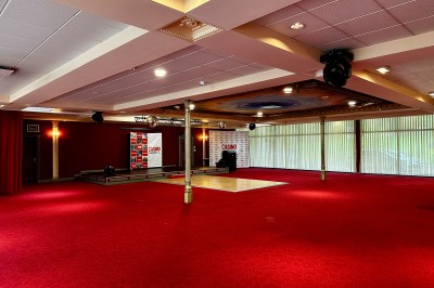 Salle de réception avec scène, piste de danse en bois, moquette rouge et plafond décoré d'une fresque.
