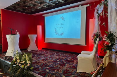 Salle de réception avec scène, piste de danse en bois, moquette rouge et plafond décoré d'une fresque.