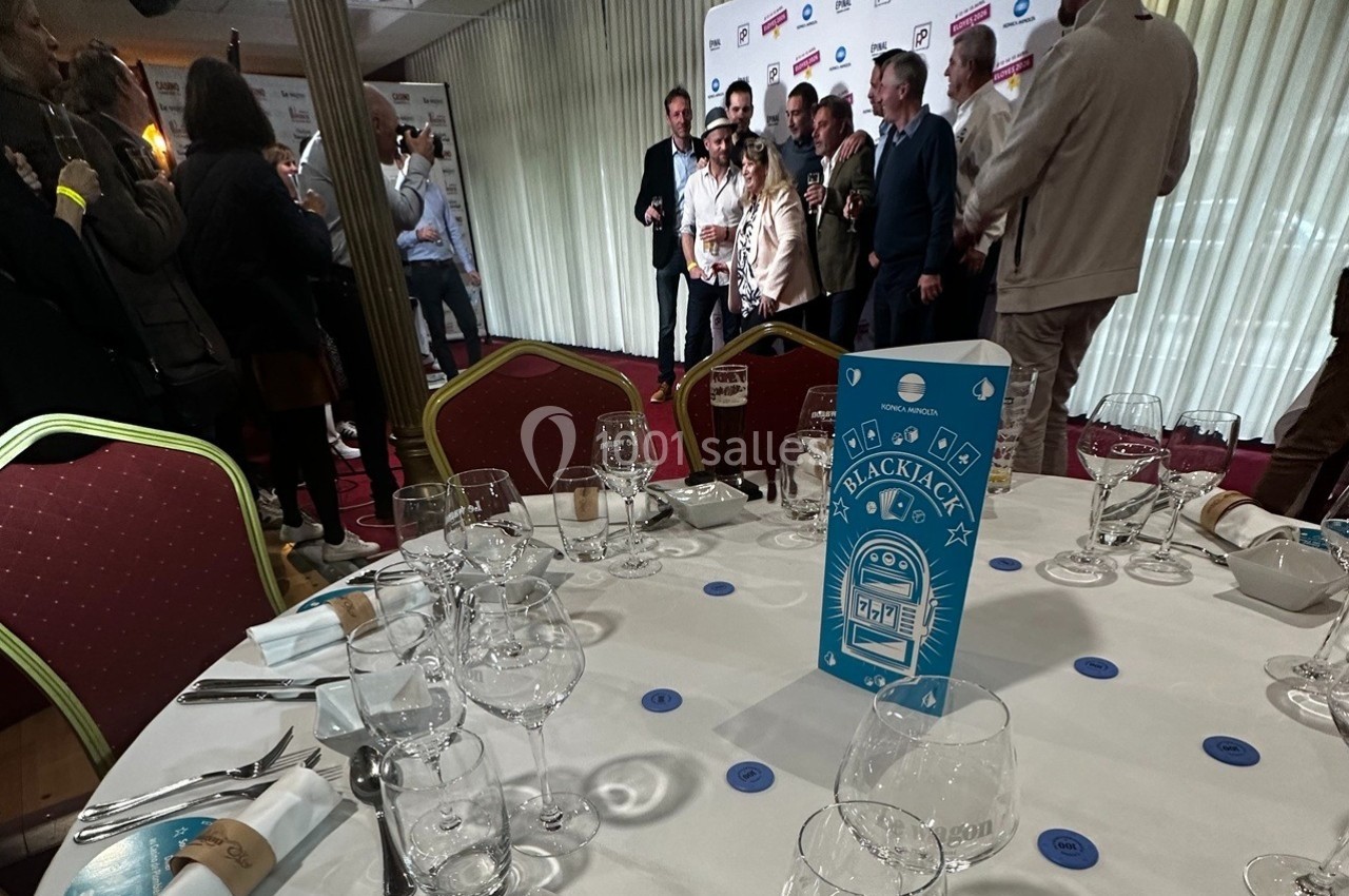 Ambiance, convivialité lors de votre soirée Groupe de personnes posant devant un mur de logos dans une salle, avec une table dressée au premier plan.